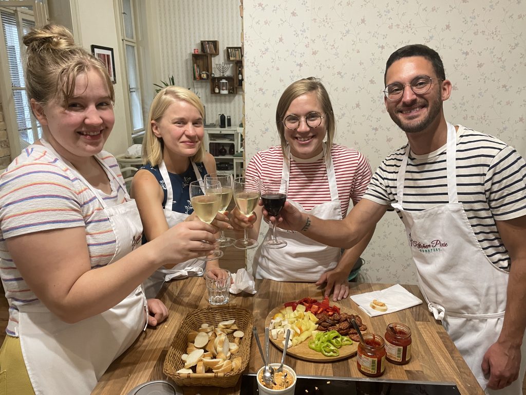 Guests toasting and tasting farmers' plate while Hungarian goulash soup is being prepared during a traditional Hungarian cooking class.