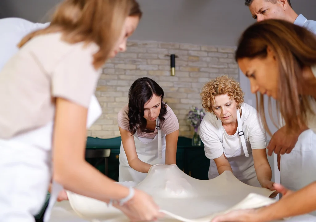 Guests fully engaged in a hands-on Hungarian strudel-making class at Flavors of Budapest Opera, stretching traditional dough by hand